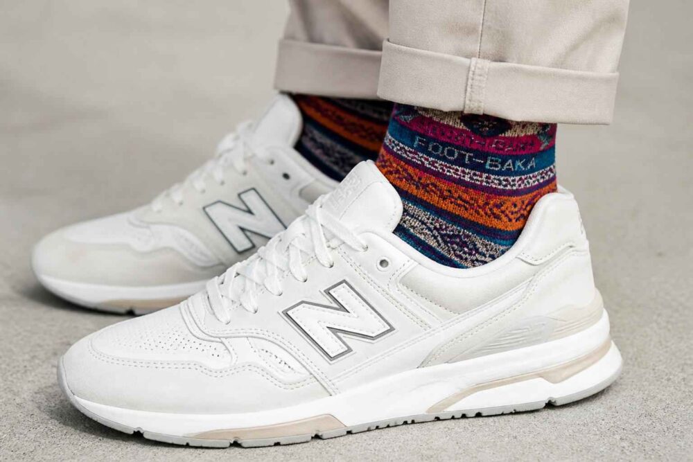 Białe buty New Balance zestawione z kolorowymi wzorzystymi skarpetami i jasnymi spodniami